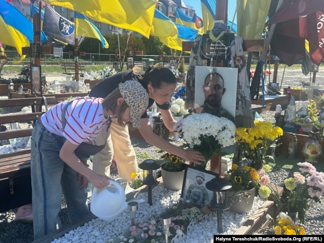 Дружина і донька біля могили чоловіка і батька Олега Хомицького