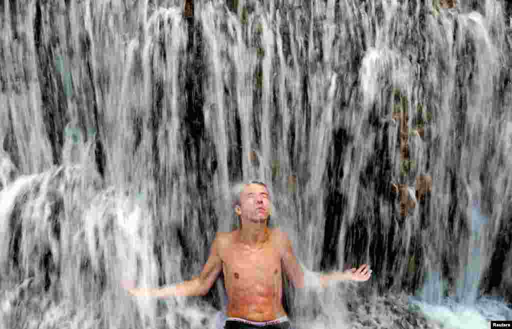 A man sits under a waterfall in the central Bosnian town of Jajce. (Reuters/Dado Ruvic)