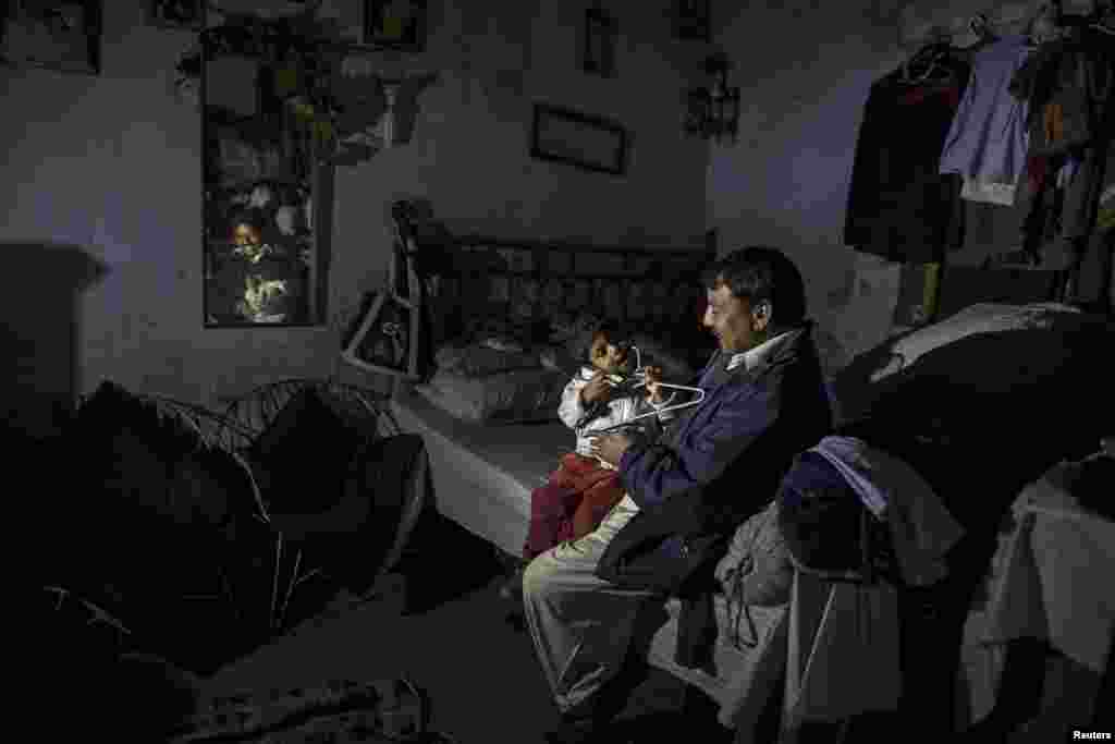 A man plays with his son as he sits in his one-room home in a Christian slum in Islamabad, Pakistan. (Reuters/Zohra Bensemra)