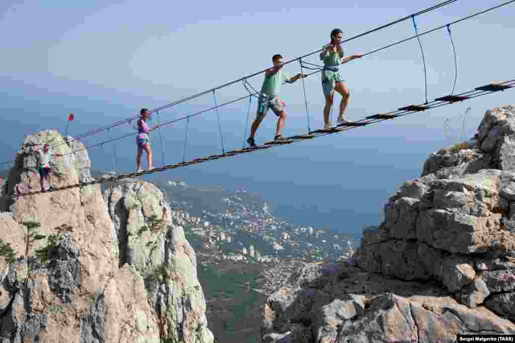 Turiștii merg pe podul suspendat Sky Trail, de pe Muntele Ai Petri din sudul Crimeii.