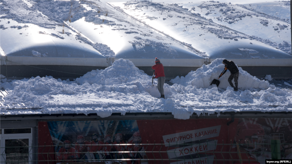 Мужчины очищают от снега крышу ледовой арены спортшколы &laquo;Наследие&raquo; в Симферополе&nbsp;