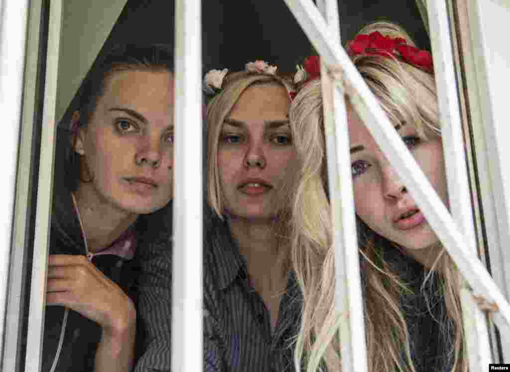 Activists from the women's rights group Femen look out a window during a court session in Kyiv. Femen says its activists were beaten up and kidnapped preemptively when they were on their way to protest against visits to Ukraine by Russian President Vladimir Putin and Russian Orthodox Church Patriarch Kirill. (Reuters/Valentyn Ogirenko)