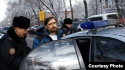 Полицейские сажают в патрульный автомобиль задержанного блогера Дмитрия Щелокова. Алматы, 21 февраля 2014 года.