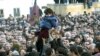 Supporters of the opposition hoist a small girl holding a flower during a rally in front of the Georgian presidential residence in Tbilisi on November 22, 2003.
