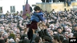 Supporters of the opposition hoist a small girl holding a flower during a rally in front of the Georgian presidential residence in Tbilisi on November 22, 2003.