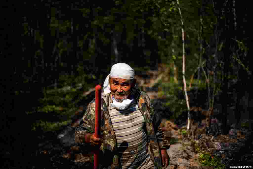 65-летний Иван Федоров помогает российским пожарным проверить пятикилометровую траншею, вырытую для борьбы с лесными пожарами в сибирском районе Якутии
