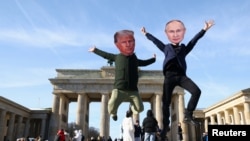 Berlində etiraz aksiyasında Donald Tramp və Vladimir Putin maskaları taxan insanlar.