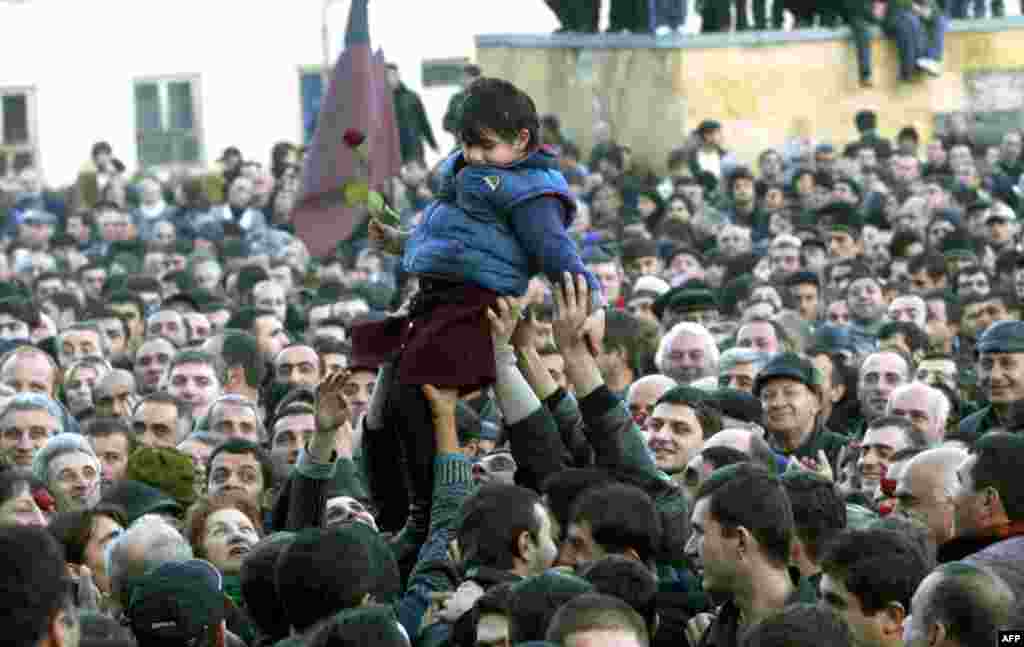 Supporters of the opposition hold up a little girl holding a flower during a rally in front of the presidential residence in Tbilisi on November 22. Georgia teetered on the brink of chaos, with Shevardnadze declaring a state of emergency and an opposition leader claiming the interim presidency after supporters overran parliament.