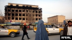 Afghans walk past a burned-out shopping center, destroyed during a deadly Taliban attack on January 18.