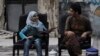 A girl holds a gun across her lap as she sits with a Free Syrian Army fighter on a street in Aleppo. (Reuters/Loubna Mrie)