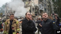 Ukrainian Prime Minister Yulia Svyrydenko (center) and Interior Minister Ihor Klymenko (right) visit the site of a multistorey residential building destroyed by a Russian missile attack in Kyiv on July 31. 