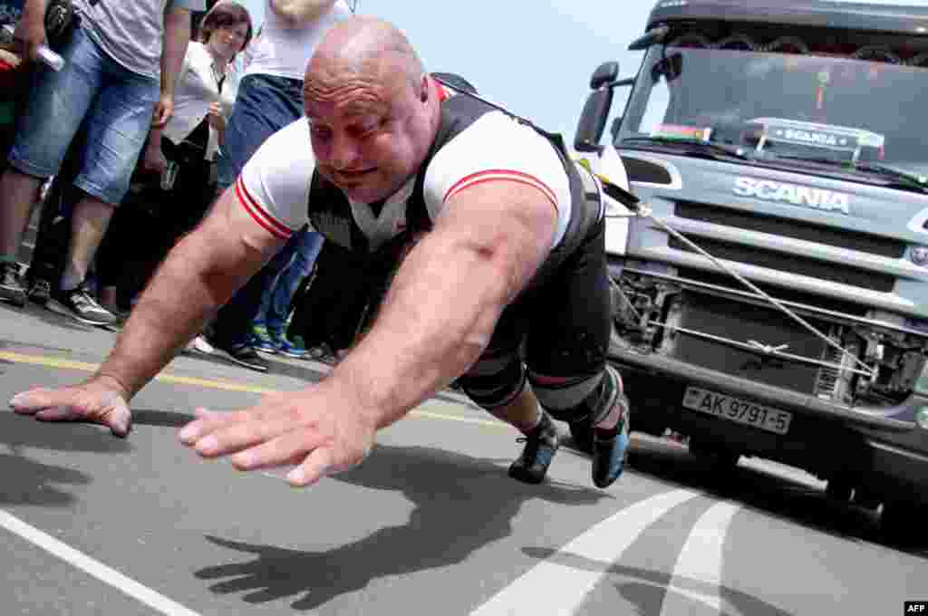 An athlete pulls a 15-ton truck during a truck-pull event marking Belarus&#39;s upcoming Independence Day in the capital, Minsk, on July 3. (AFP/Sergei Gapon)