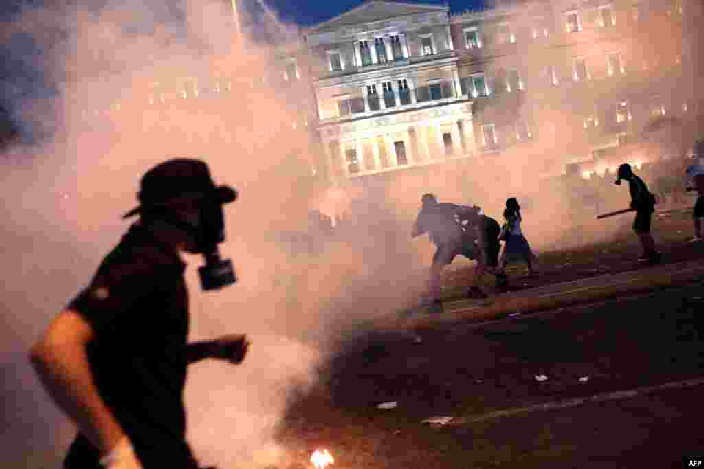 A protester clashes with riot police in front of the Greek parliament in Athens amid tensions over the acceptance of bailout conditions laid down by Brussels. (AFP/Angelos)