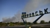 A man rides a bicycle along a road past a sign indicating the town of Pokrovsk as smoke rises in the background, outside the town of Pokrovsk, Donetsk region, on September 20, 2024, amid the Russian invasion of Ukraine.