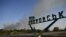 A man rides a bicycle along a road past a sign indicating the town of Pokrovsk as smoke rises in the background, outside the town of Pokrovsk, Donetsk region, on September 20, 2024, amid the Russian invasion of Ukraine.