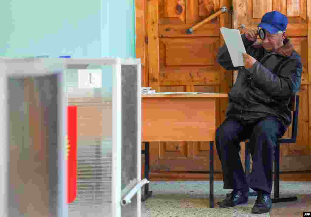 A man closely inspects a ballot paper before voting in Russian regional elections at a polling station in the town of Kostroma, some 300 kilometers outside Moscow. (AFP/Dmitry Serebryakov)