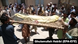 People shift the body of one of the polio vaccination workers who was killed in Jalalabad on June 15.