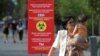 Люди проходят мимо плаката с информацией о мерах профилактики коронавирусной инфекции. Алматы, 12 июля 2020 года. REUTERS/Pavel Mikheyev.