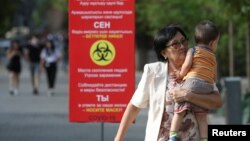 Алматы көшесінде бала көтеріп келе жатқан әйел. 12 шілде 2020 жыл.