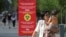 Люди проходят мимо плаката с информацией о мерах профилактики коронавирусной инфекции. Алматы, 12 июля 2020 года. REUTERS/Pavel Mikheyev.