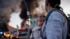 A woman with a child walks looks at the aftermath of a Russian missile strike on Kyiv on September 8.