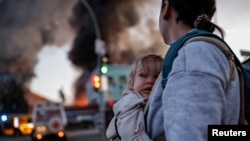 A woman with a child walks looks at the aftermath of a Russian missile strike on Kyiv on September 8.