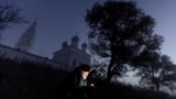 RUSSIA -- A photographer uses his mobile phone near The Church of the Kazan Icon of the Mother of God in the morning mist at dawn in the village of Osenevo, Yaroslavl region, October 6, 2024.