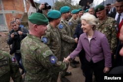 Predsjednica Europske komisije Ursula von der Leyen rukuje se s vojnikom EUFOR-a, dok posjećuje područje pogođeno nedavnim poplavama u Donjoj Jablanici, na jugu BiH, 24. 11. 2024.