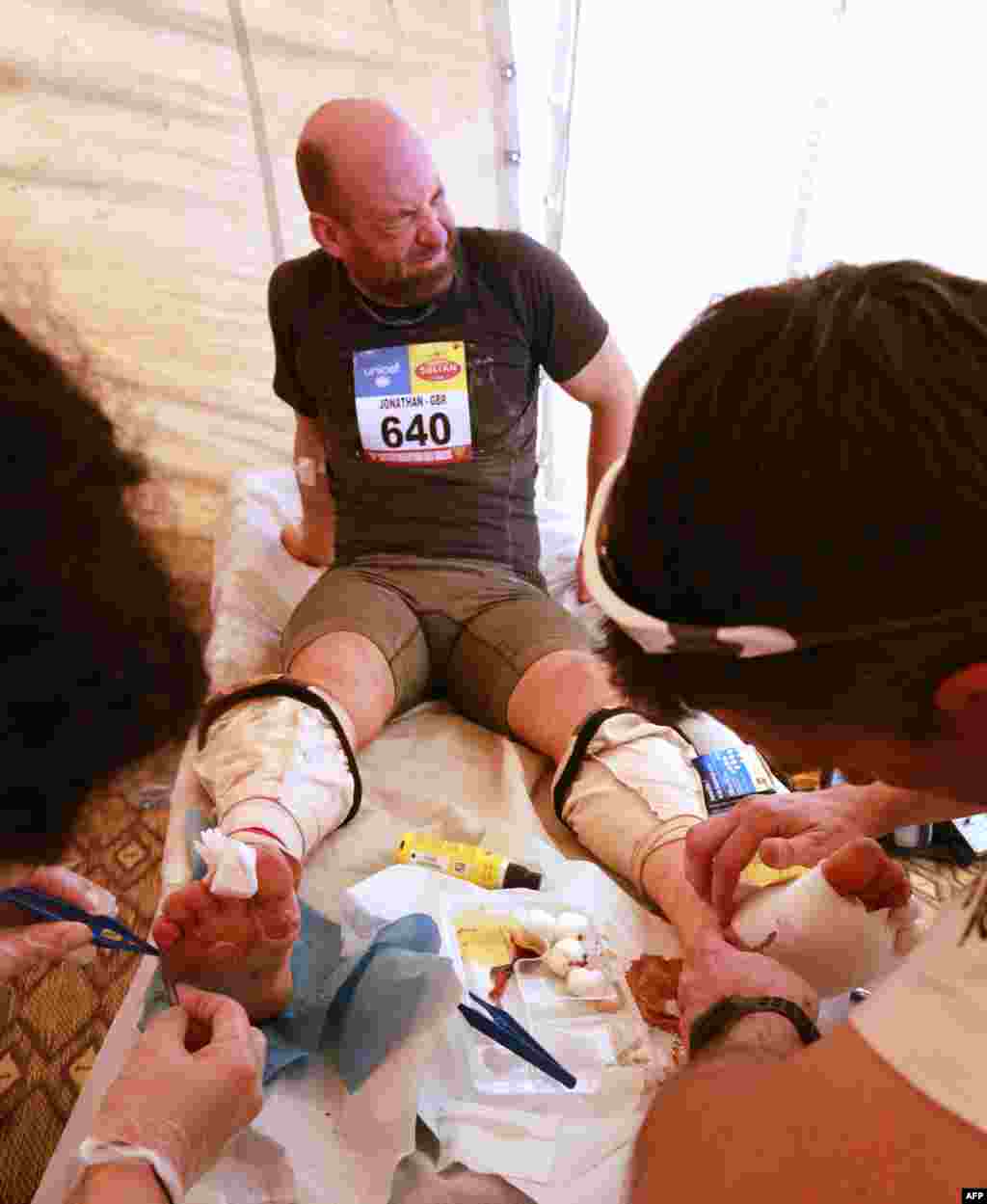A competitor receives treatement on his feet during the 28th edition of the grueling 224-kilometer Marathon des Sables in Morocco. Competitors must carry all of their equipment on their backs during the seven-day race. Only carefully rationed bottles of water and open-sided local tents are provided by the organizers. (AFP/Pierre Verdy)