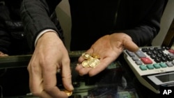 An Iranian goldsmith counts his gold coins at a gold market in the main old Bazaar in Tehran. File photo