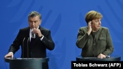 German Chancellor Angela Merkel (right) and Uzbek President Shavkat Mirziyoev speak to reporters in Berlin on January 21.