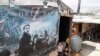 Syrian refugees rest beside a film poster being used as part of a tent in an informal settlement in Zahle in the Bekaa Valley, Lebanon. (Reuters/ Mohamed Azakir)