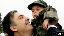 President Michael Saakashvili holds a child in a military uniform in Tbilisi in August, during a ceremony on the first anniversary of the war with Russia.