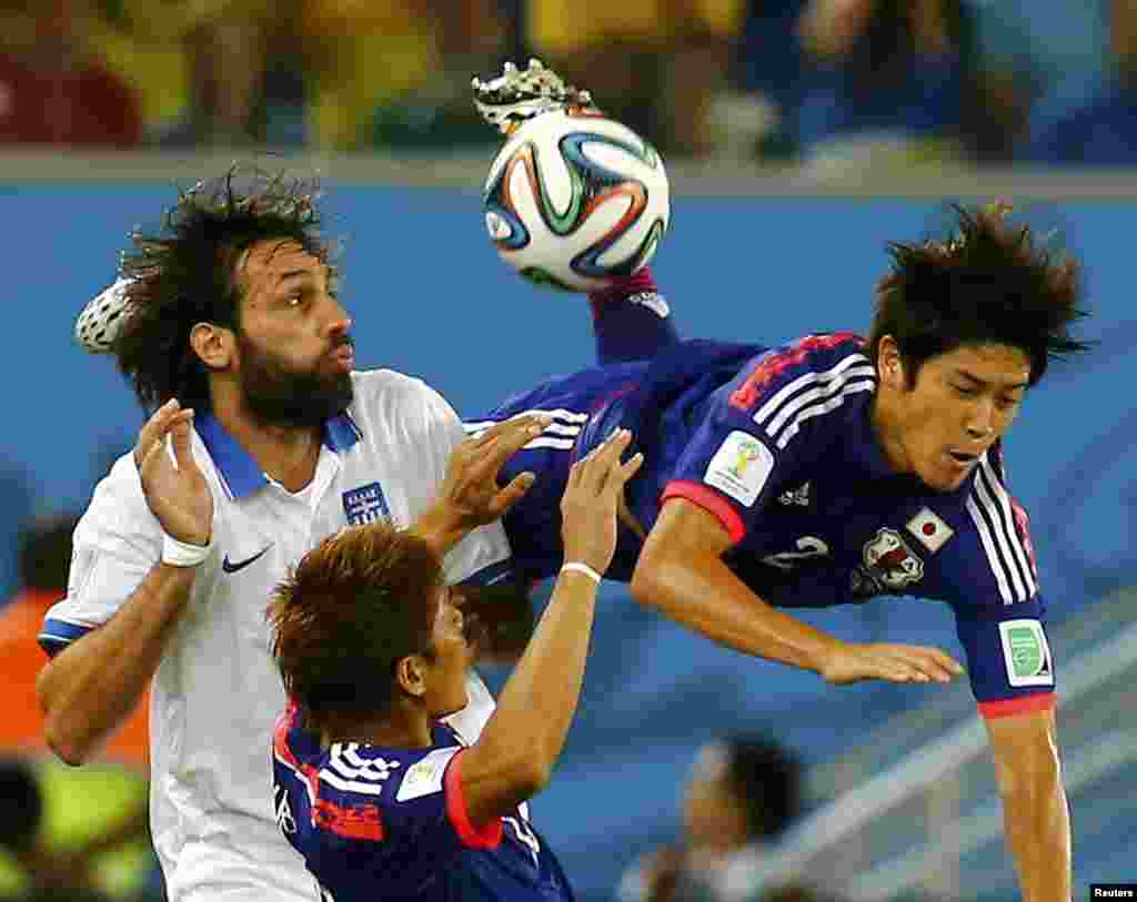 Yunanıstan komandasının hücumçusu Giorgios Samaras yaponiyalı Atsuto Uchida-ya qarşı qaydanı pozur.