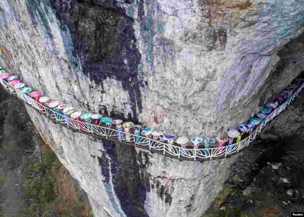 Women wearing cheongsam gowns pose for pictures on a walkway along a cliff during an event in China's Chongqing Municipality on March 26. (Reuters)