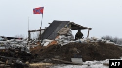 A pro-Russian soldier stands guard at a checkpoint in Enakieve, 25 kilometers from the eastern town of Debaltsevo, on January 29.