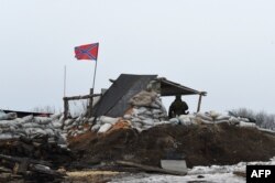 A pro-Russian fighter stands guard at a checkpoint in Enakieve, 25 kilometers from the eastern town of Debaltsevo, on January 29.