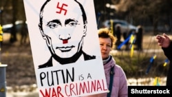 Женщина с плакатом «Путин – военный преступник» во время акции с требованием России прекратить войну против Украины. Вильнюс, Литва, 2 марта 2022 года