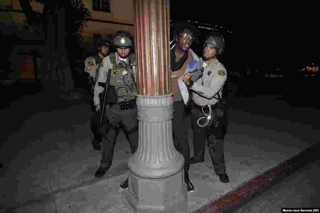 Poliția îl reține pe unul din protestatari pentru încălcarea regimului de circulație pe timp de noapte, Los Angeles, 3 iunie