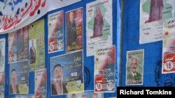 An Iraqi police officer in front of campaign posters on blast wall outside a Baq'ubah polling station