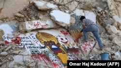 A Syrian graffiti artist puts the final touches on his anti-Russian mural painting amid the rubble of a damaged building in the town of Binnish in Syria's rebel-controlled Idlib province. (file photo)