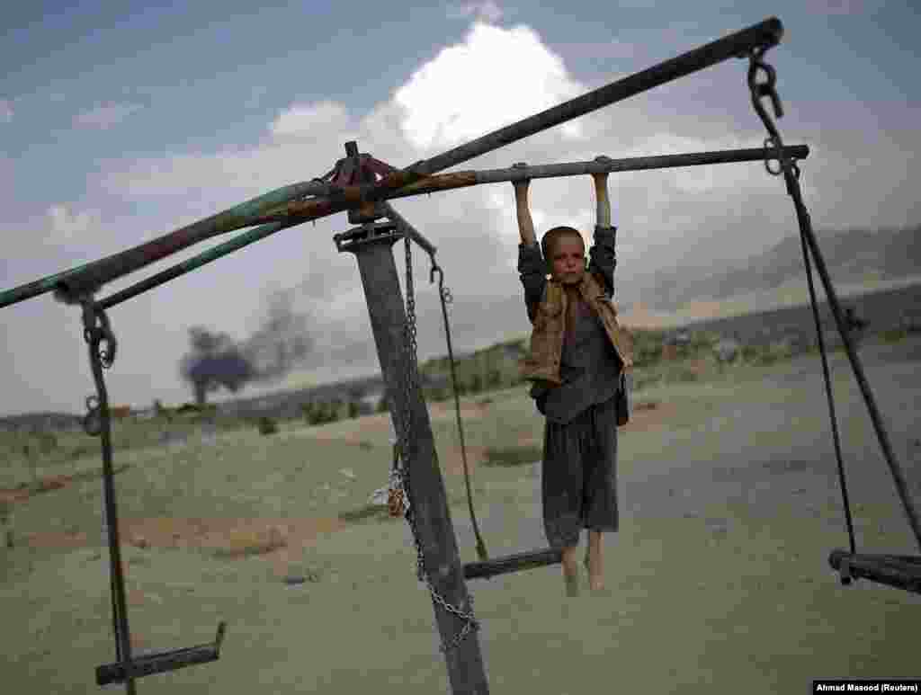 An Afghan boy plays on a merry-go-round on a hill top in Kabul, July 20, 2015. (Reuters/Ahmad Masood)