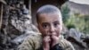 A young girl waits for relief aid outside her home destroyed in Chitral in late October.