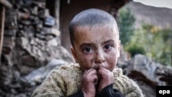 A young girl waits for relief aid outside her home destroyed in Chitral in late October.