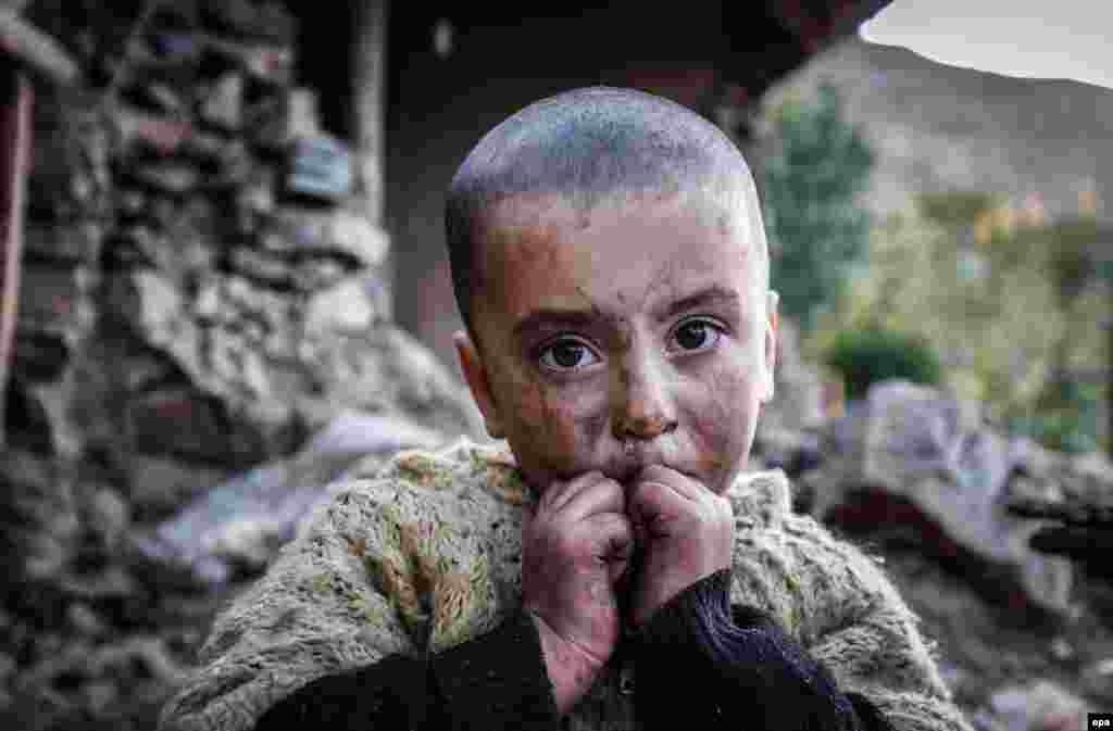 A young girl waits for relief aid outside her home, which was destroyed in a 7.7-magnitude earthquake, in Reshun, Chitral Valley, Pakistan. Some 400 people were killed in Afghanistan and Pakistan. Emergency services and members of the armed forces continue operations to rescue those affected. (epa/Omer Saleem)