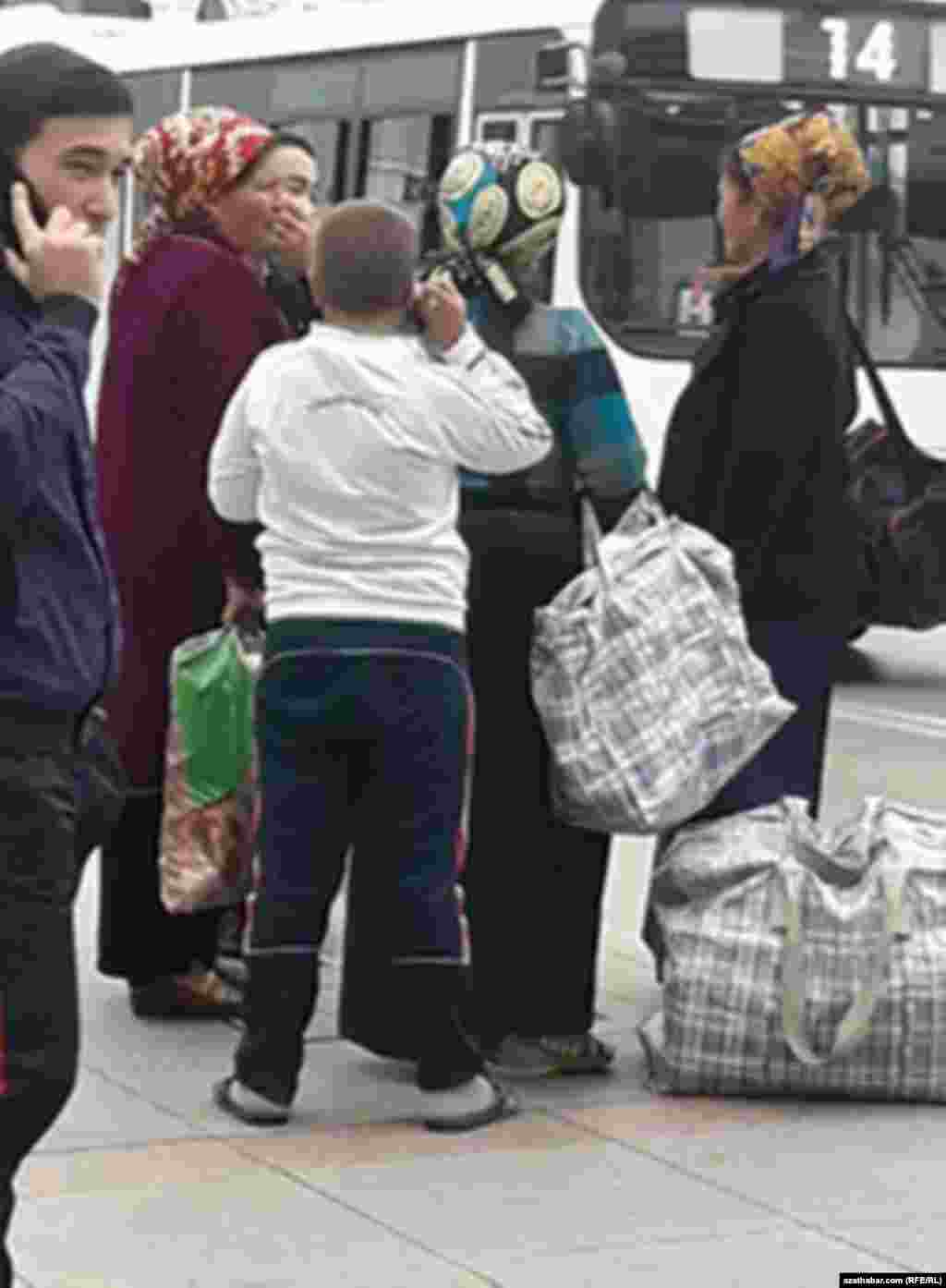 Aşgabatda el goşlary bilen awtobusyň gelerine garaşyp duran ýolagçylar