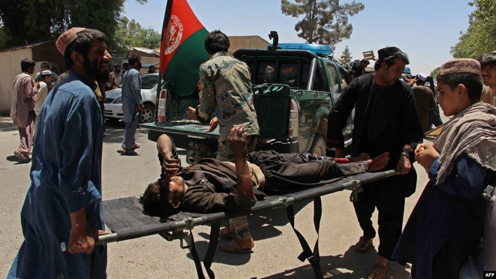 Afghan men carry a victim of a powerful car bomb in Lashkar Gah on June 22.