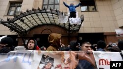 Russian protesters hold up a poster showing Turkish President Recep Tayyip Erdogan as a puppet of Islamic State militants during a rally in front of the Turkish Embassy in Moscow on November 25.