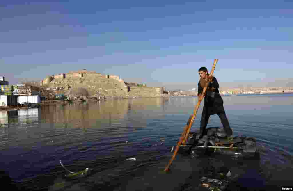 An Afghan boy rows a homemade raft on a lake in Kabul. (Reuters/Mohammad Ismail)