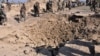 FILE: Afghan soldiers stand near a crater after a car bomb exploded which targeted an Afghan National Army (ANA) base in Khost province in March.